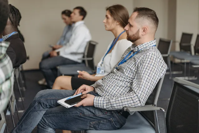 Adults attending a business seminar, attentively listening with notebooks and smartphones. Primary Market Research: Consent, Incentives, Recruitment