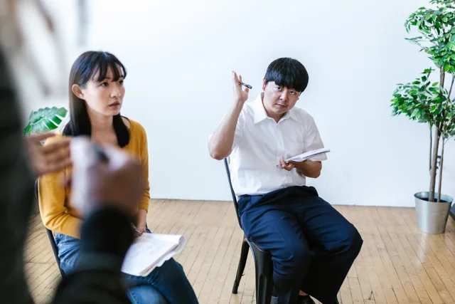 Diverse group engaged in an interactive discussion in a bright office setting, with one individual raising a question. How consumer research costs compare in New York, Chicago and Austin